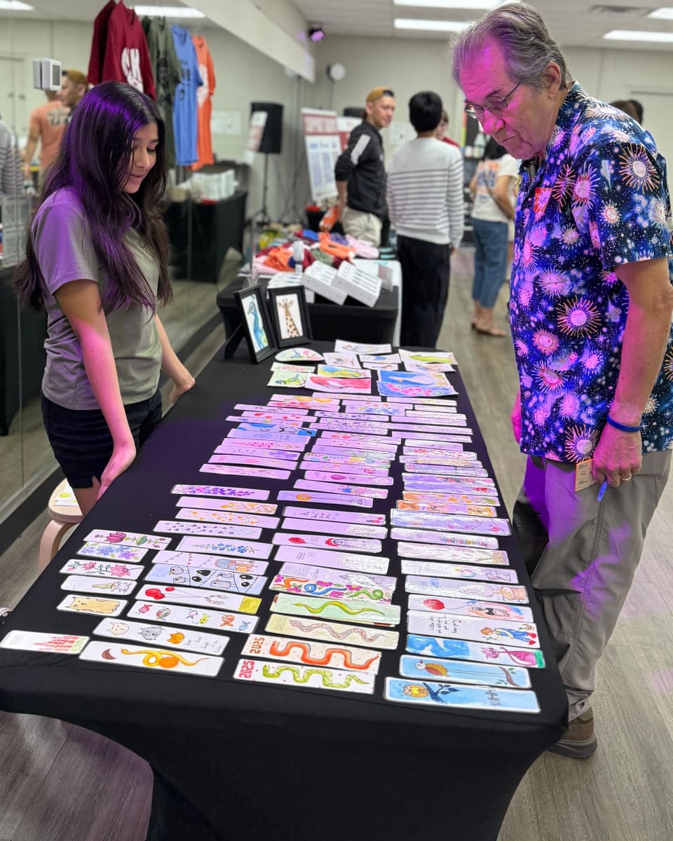 Viti at her table of handmade bookmarks while a customer looks them over