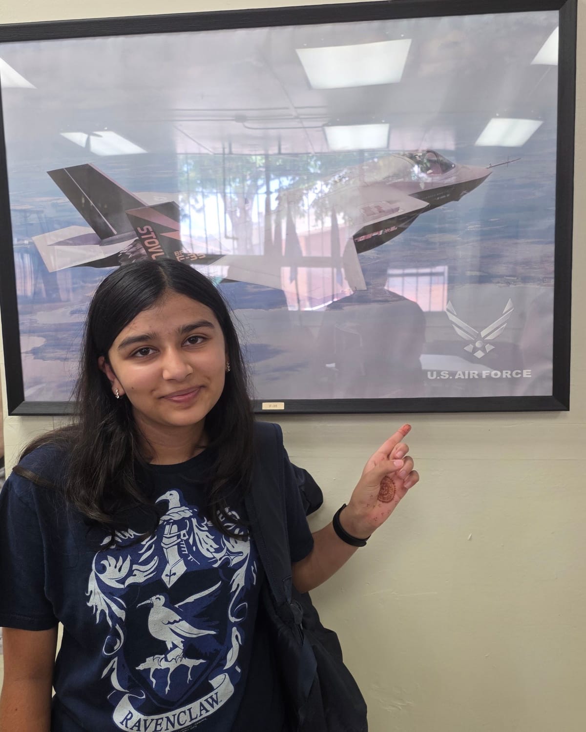 Viti smiling and pointing to an F-35 poster on the wall
