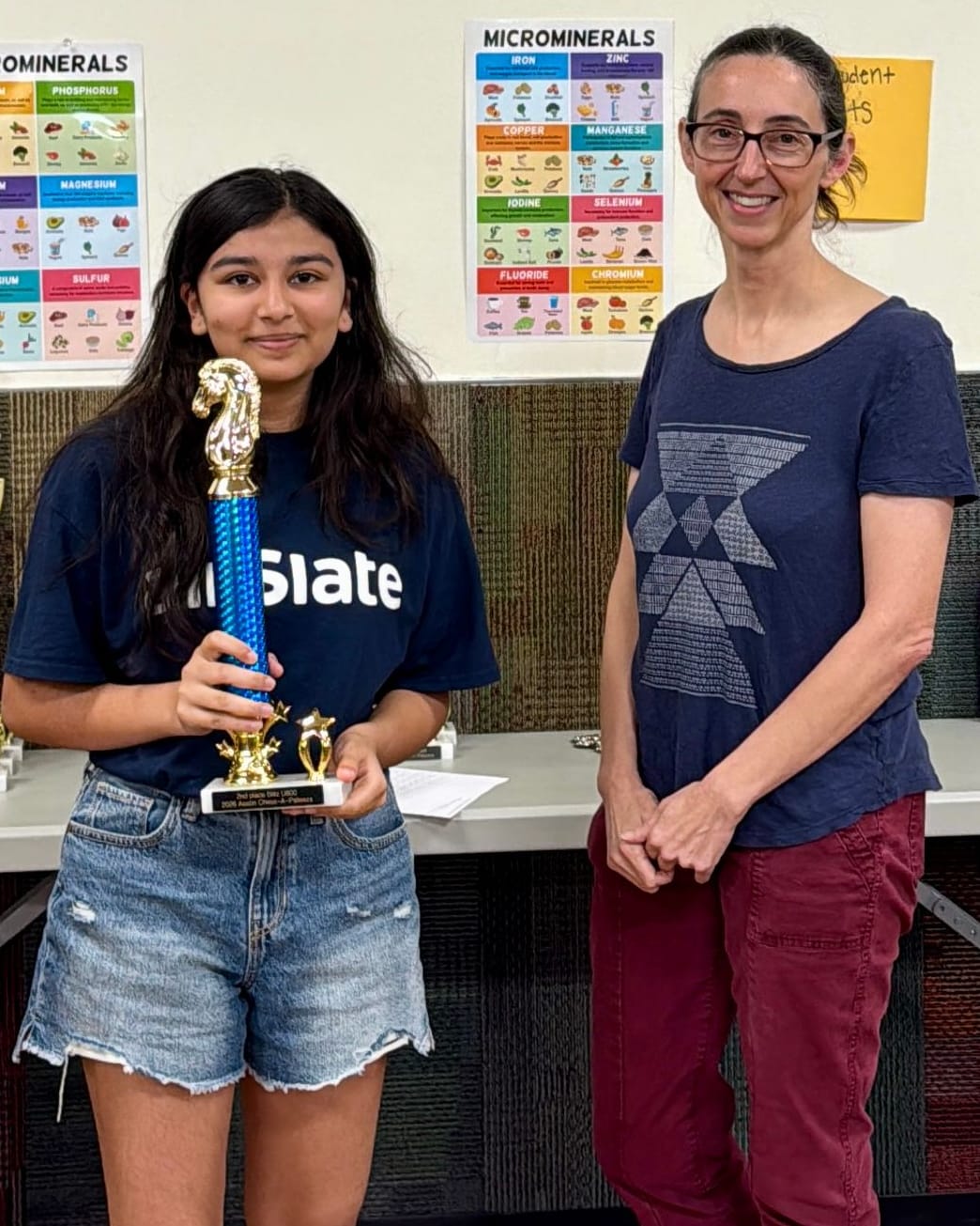 Viti holding her 2nd place trophy next to a tournament organizer