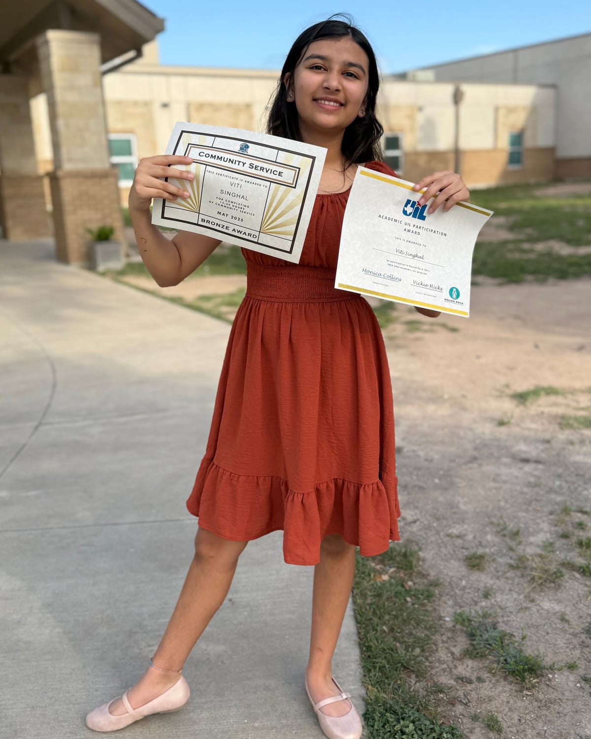 Viti smiling and holding up her community service award certificate