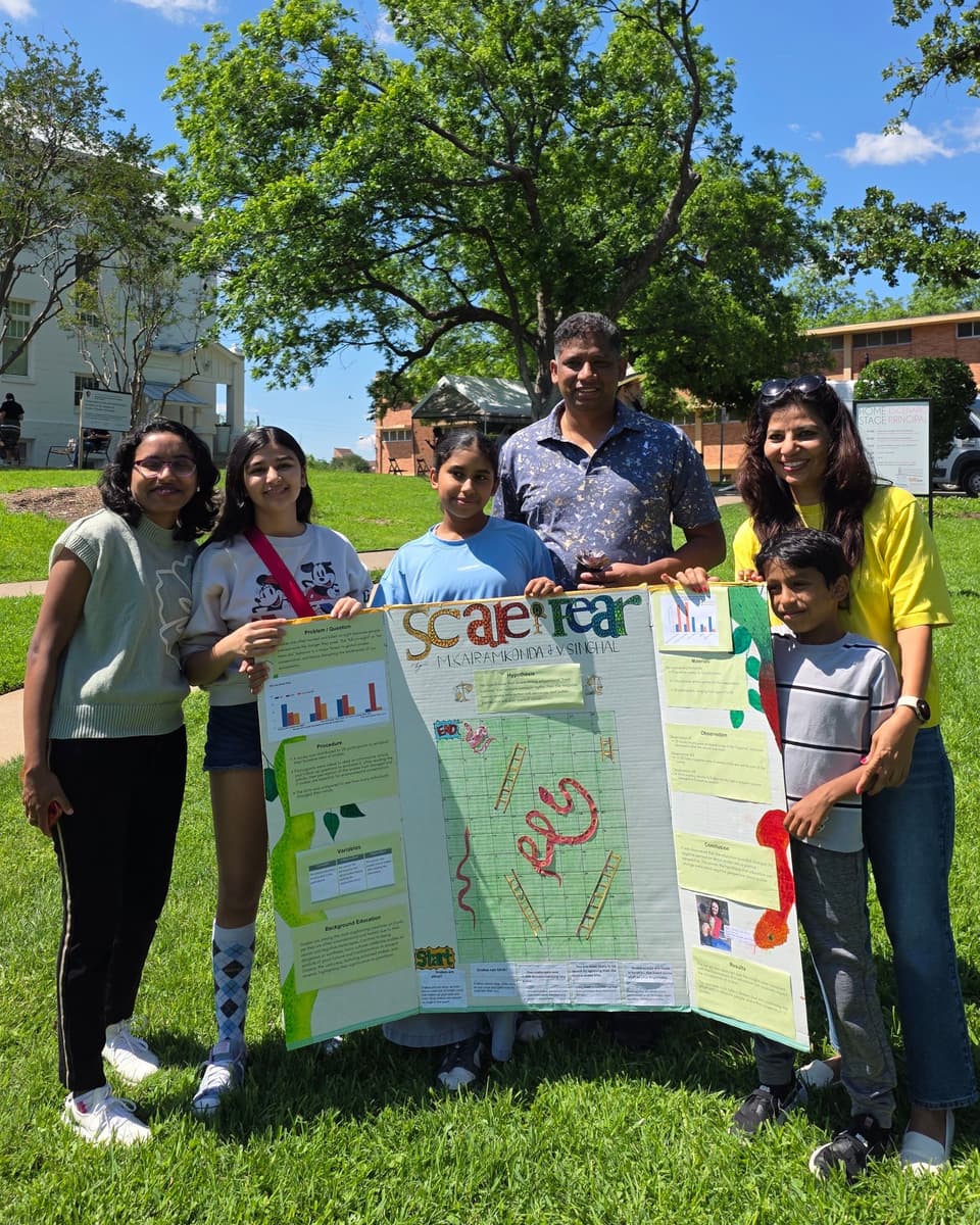 Viti and her teammate holding their snake-awareness project board in a group photo on the lawn