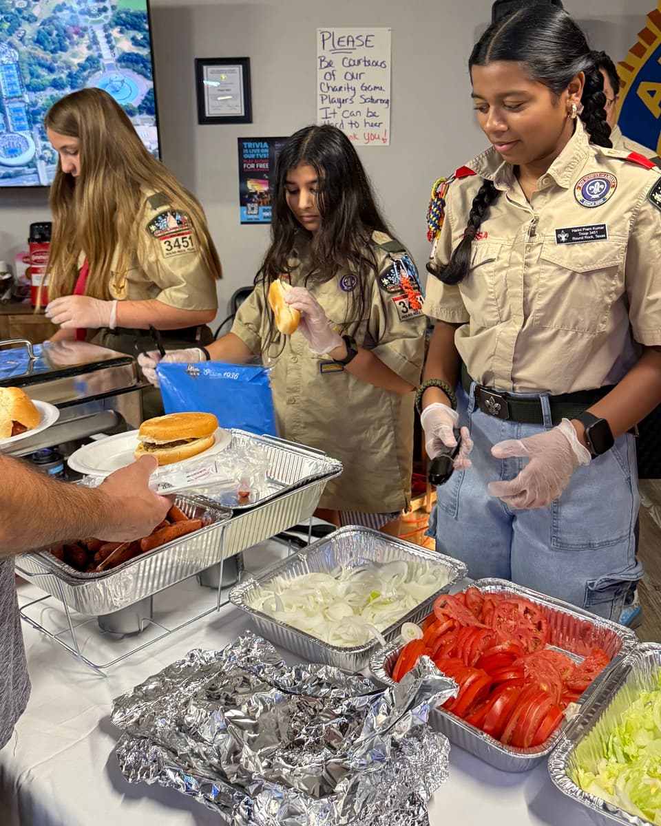 Viti in her Scouts uniform serving food between two fellow scouts