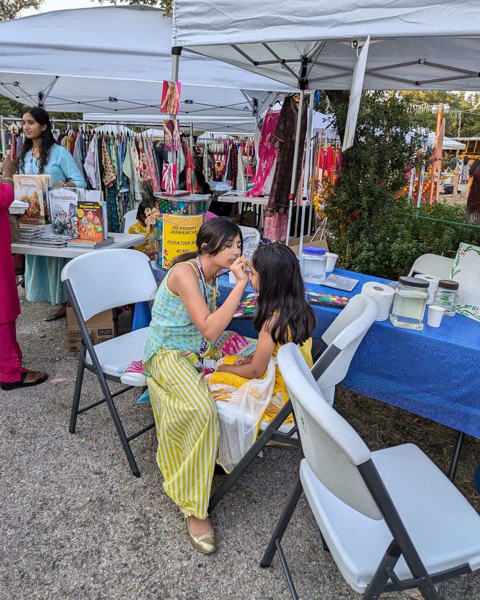 Viti painting a design on a young girl's face at her festival booth